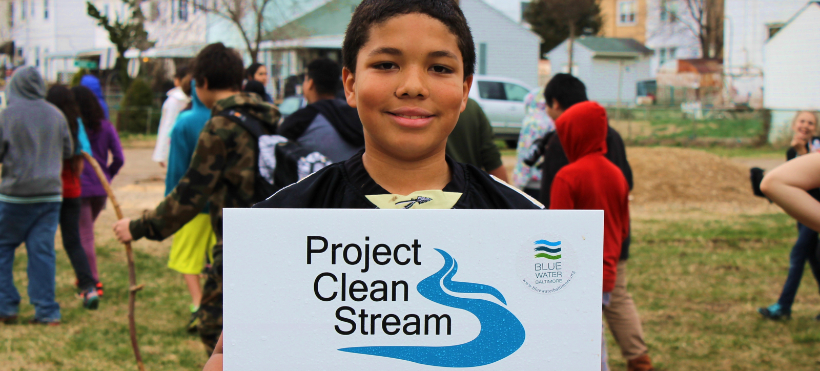 a young boy holding up a sign that says project clean stream