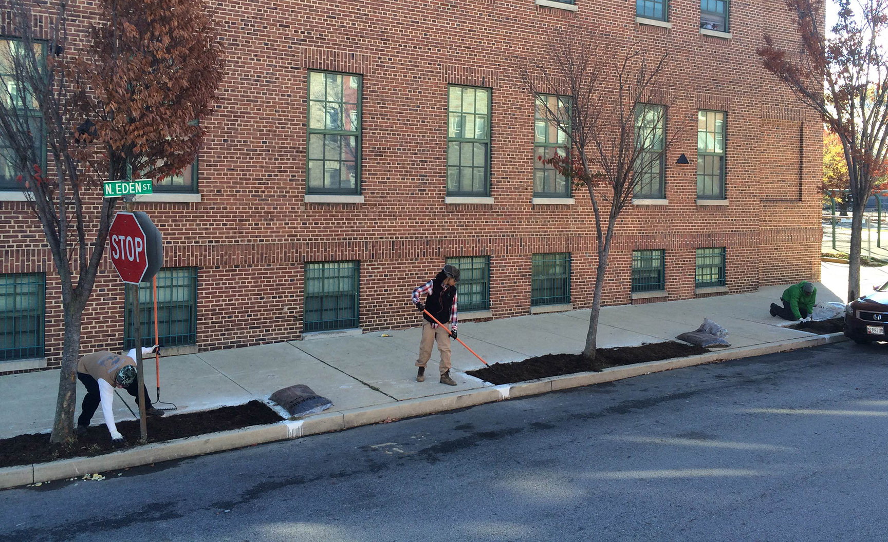 a woman is shoveling the ground in front of a brick building