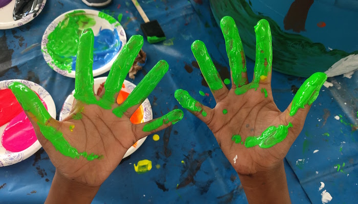 two hands with green paint on them
