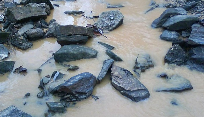 rocks and water in muddy area next to road