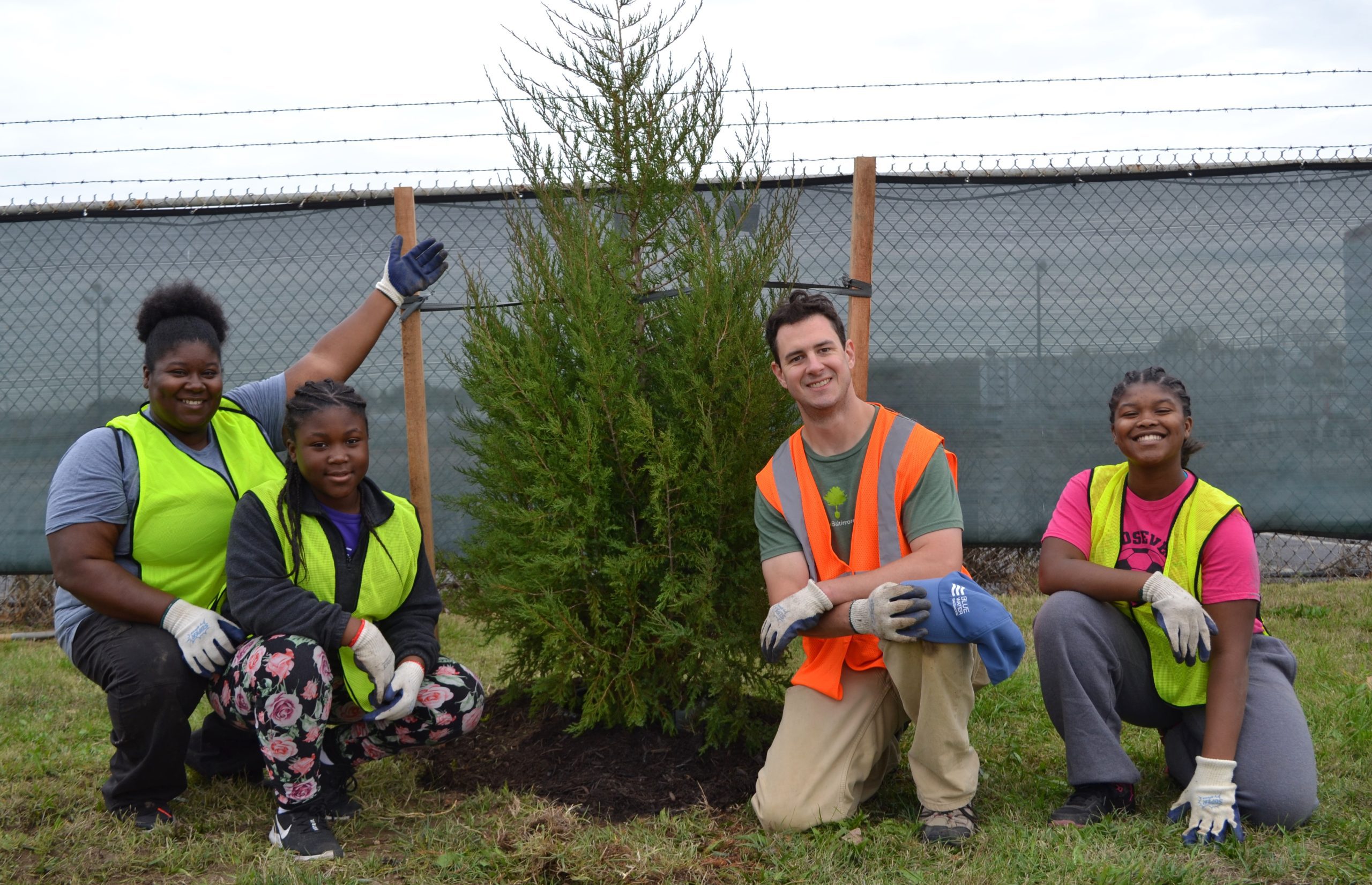 Four volunteers smiling in front of a tree they finished planting at a tree planting dedicated to late Rep. Elijah Cummings (October 26, 2019).