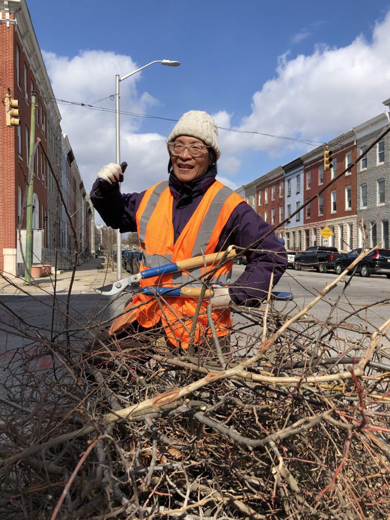 a man in an orange safety vest standing next to a pile of branches