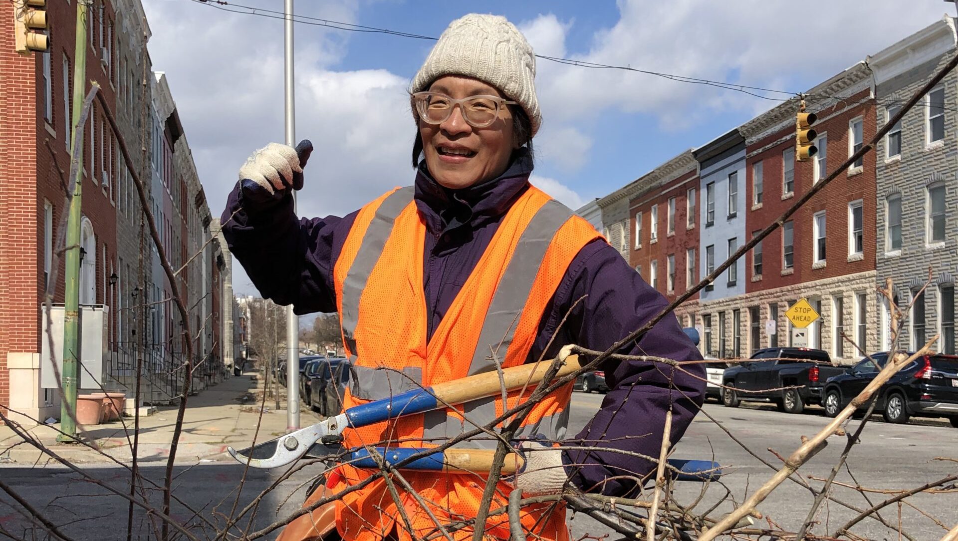 a man in an orange safety vest standing next to a pile of branches