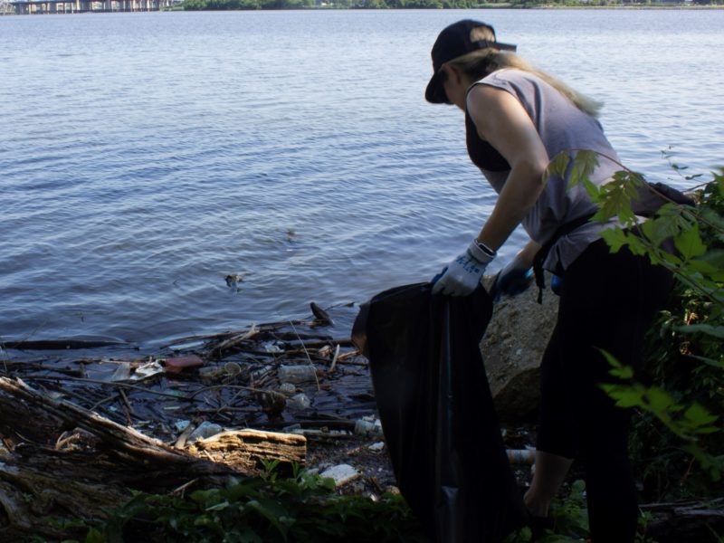 a woman is picking up trash near the water