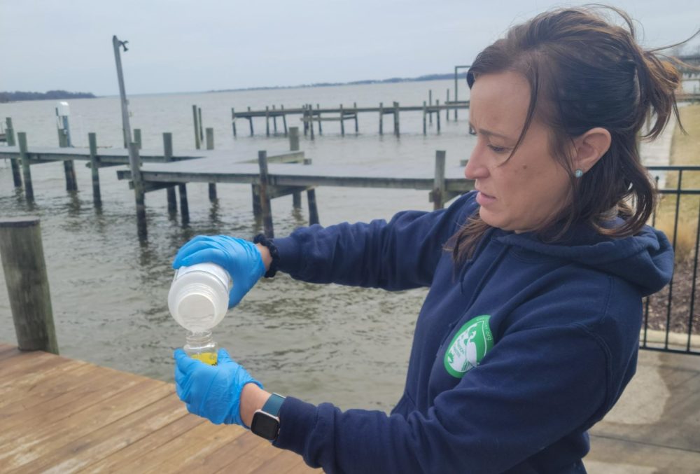 a woman in blue gloves is holding a bottle