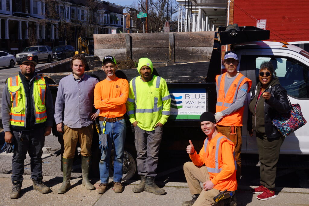 The BWB restoration team standing next to each other in front of a truck with the Blue Water Baltimore logo