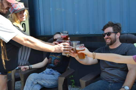 Four hands holding and clinking together pint glasses with beer at Cheers to Clean Water 2019.