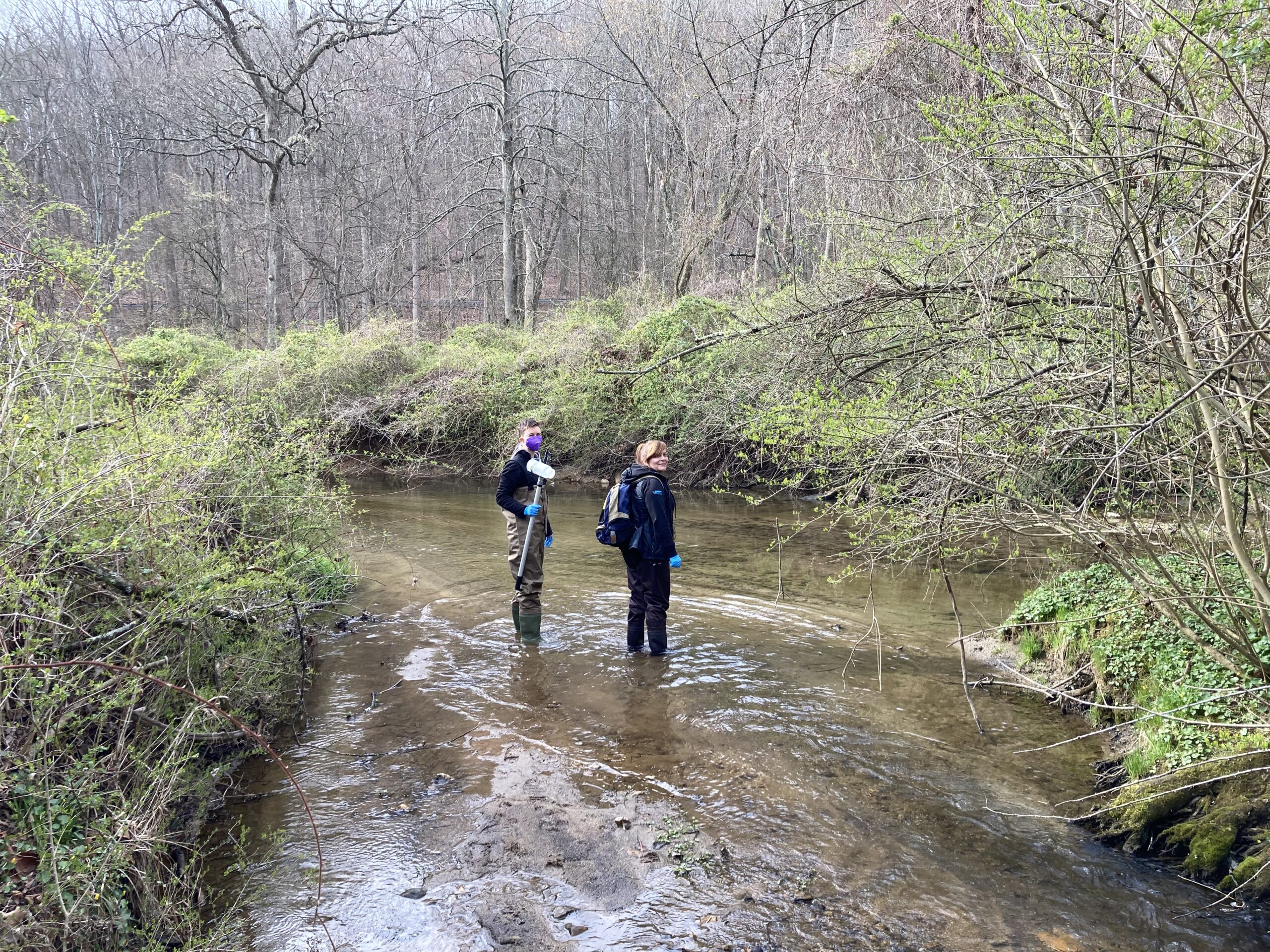 two people are standing in the middle of a stream