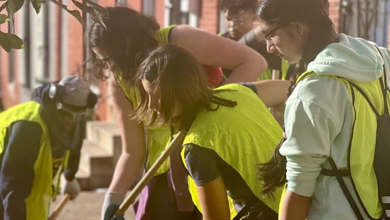 a group of people in yellow vests shoveling dirt