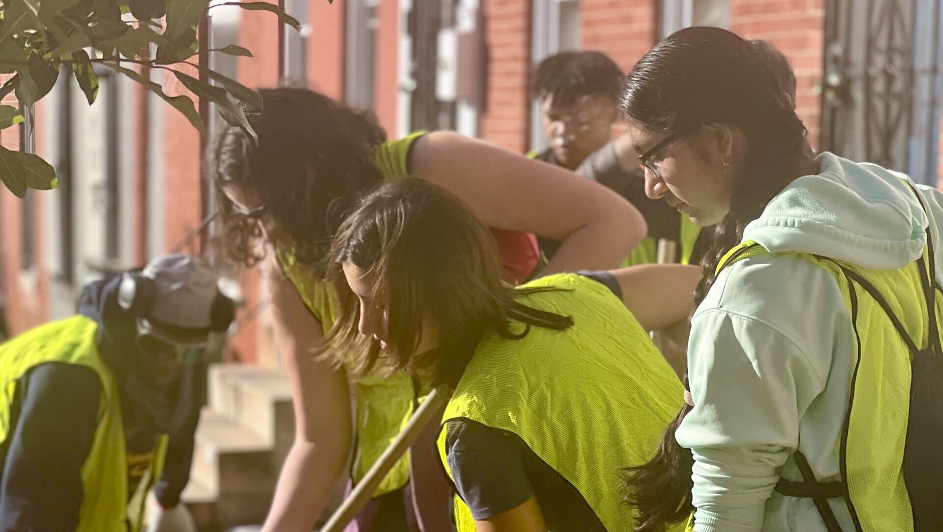 a group of people in yellow vests shoveling dirt