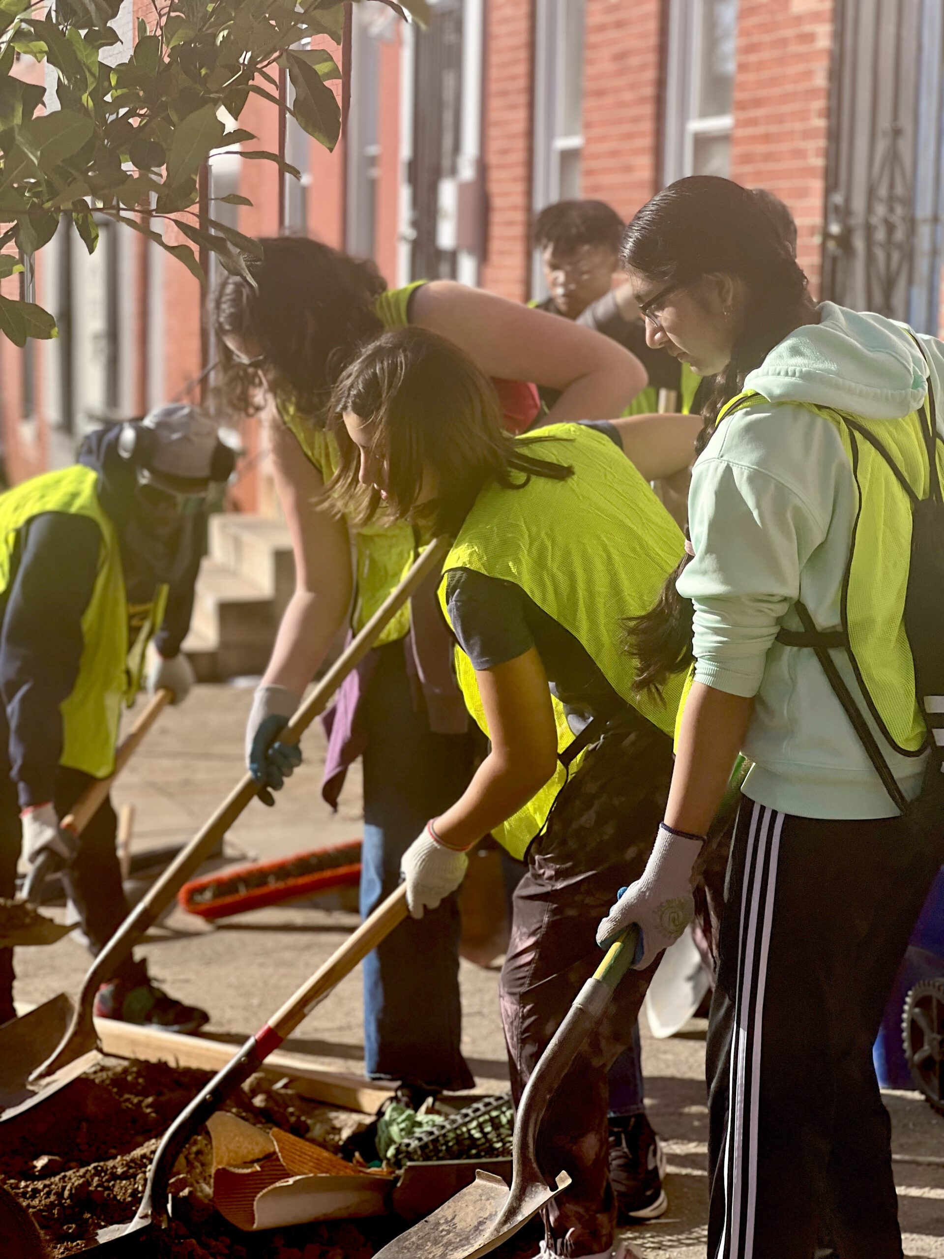 a group of people in yellow vests shoveling dirt
