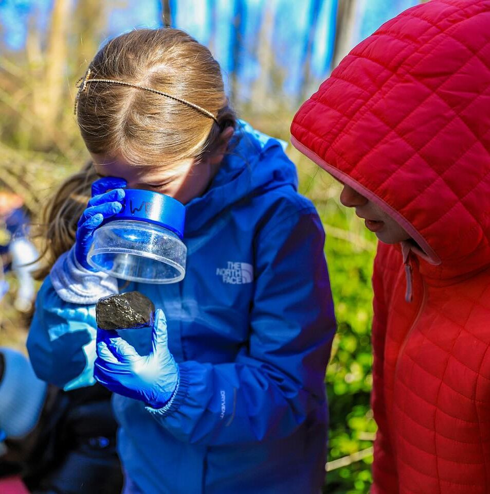 two young girls looking at something in a jar