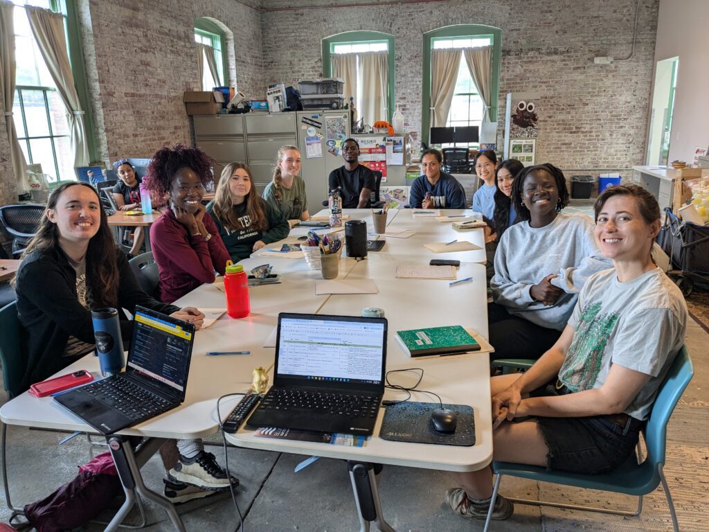 a group of people sitting around a table with laptops