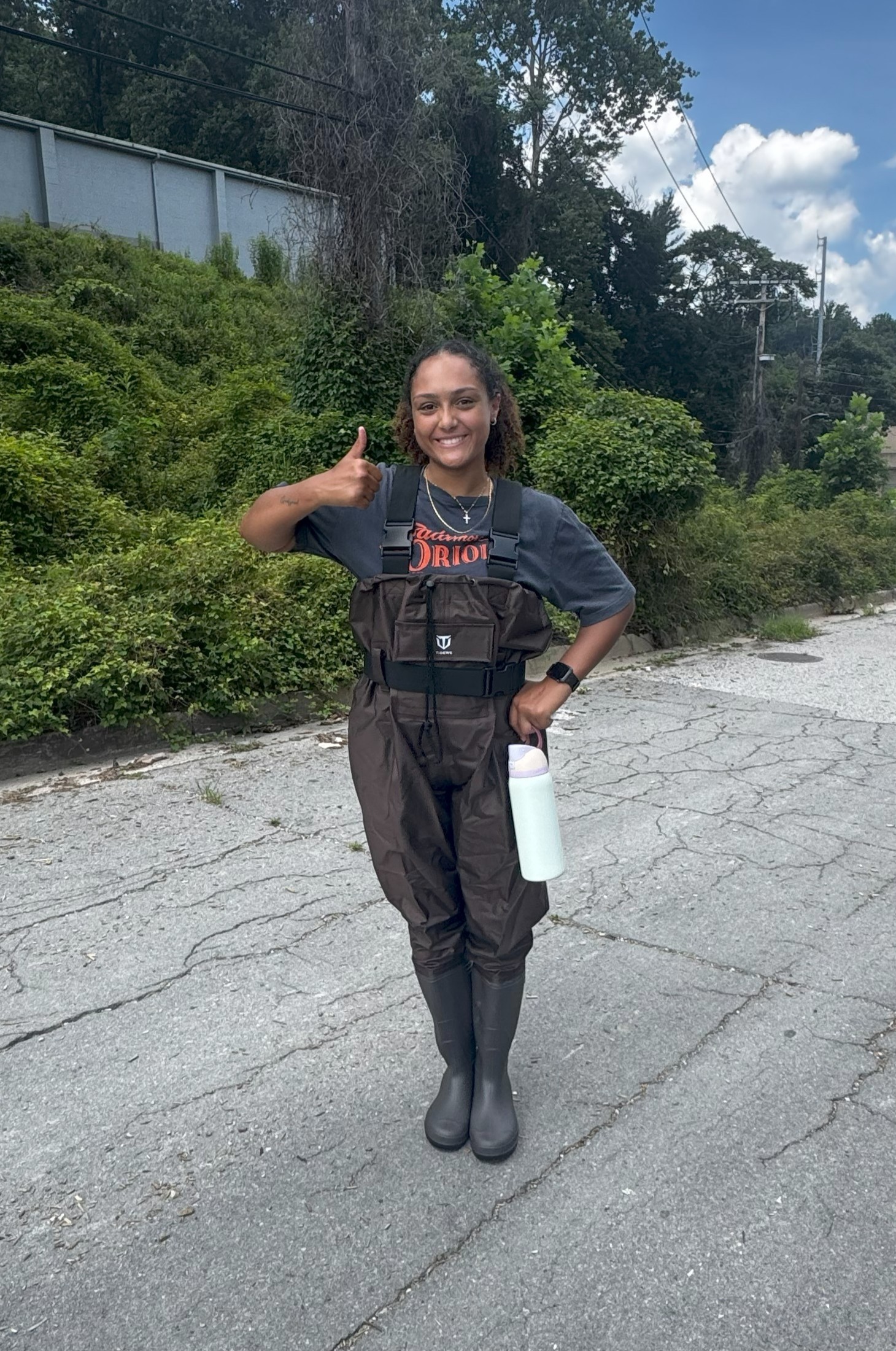 a woman standing in the middle of a road giving a thumbs up