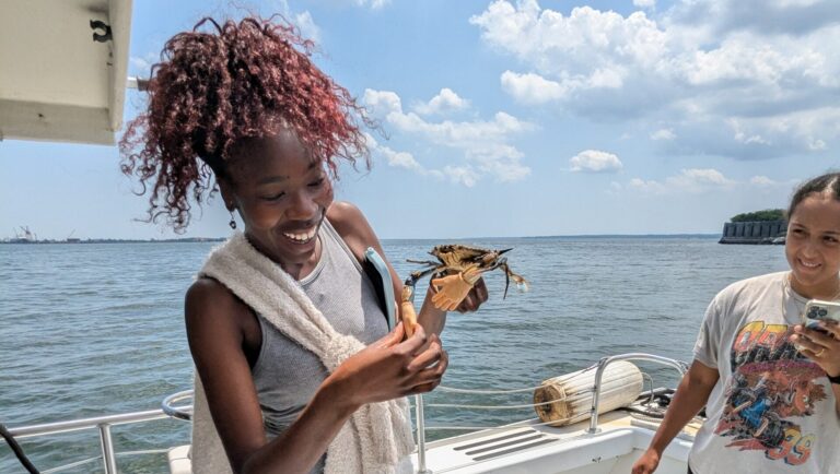 two girls on a boat with a crab in their hands