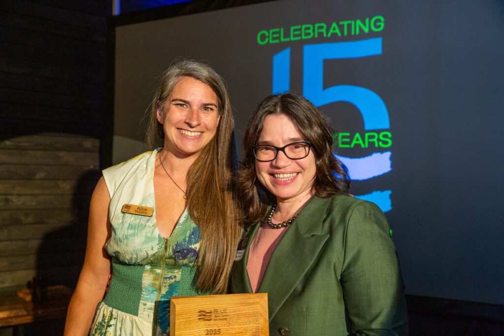 two women standing next to each other holding an award