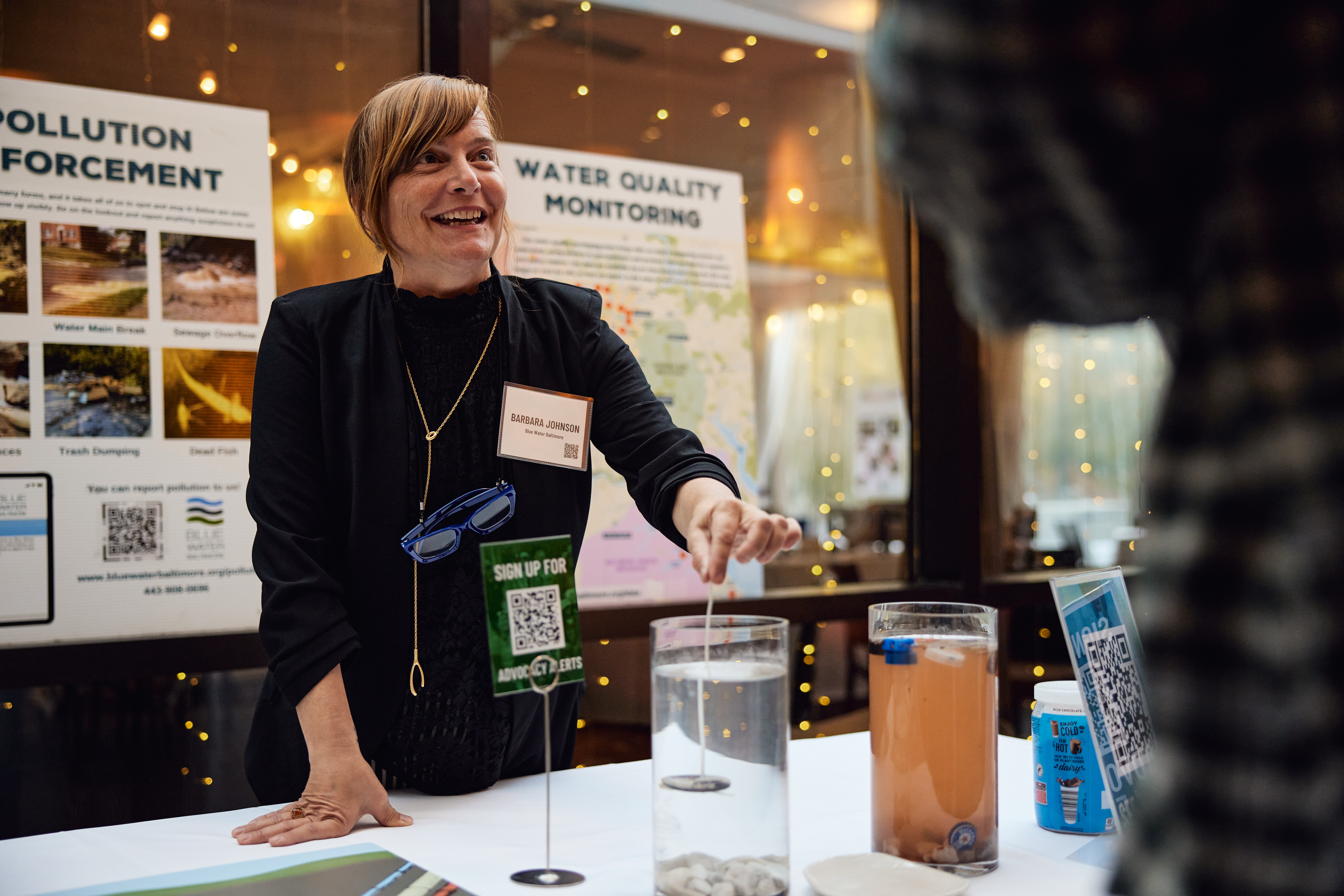 a woman standing at a table with a glass of water
