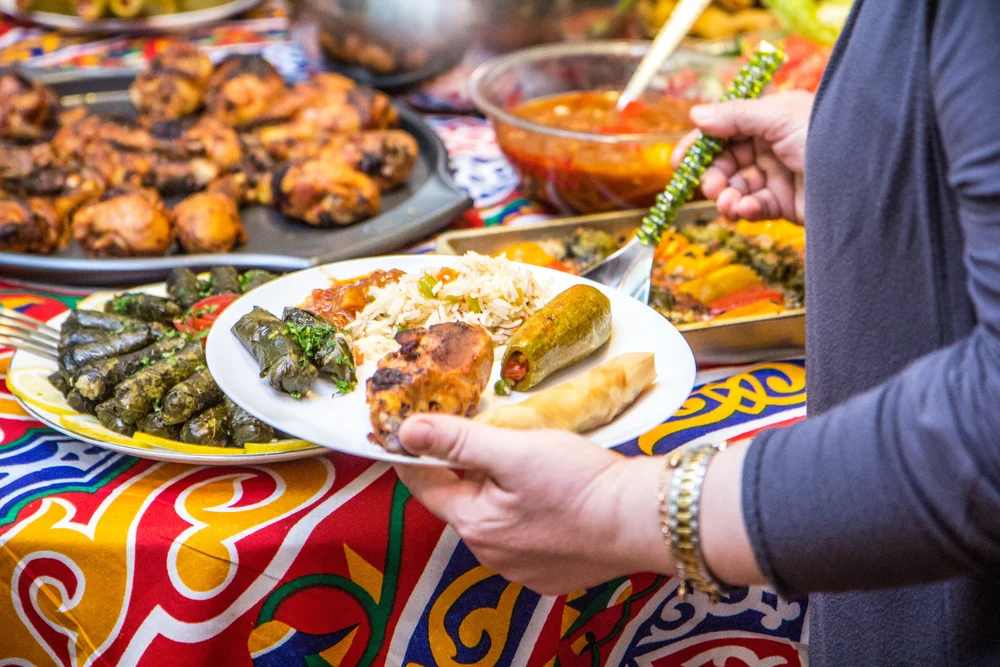 a woman holding a plate of food in front of a table full of food