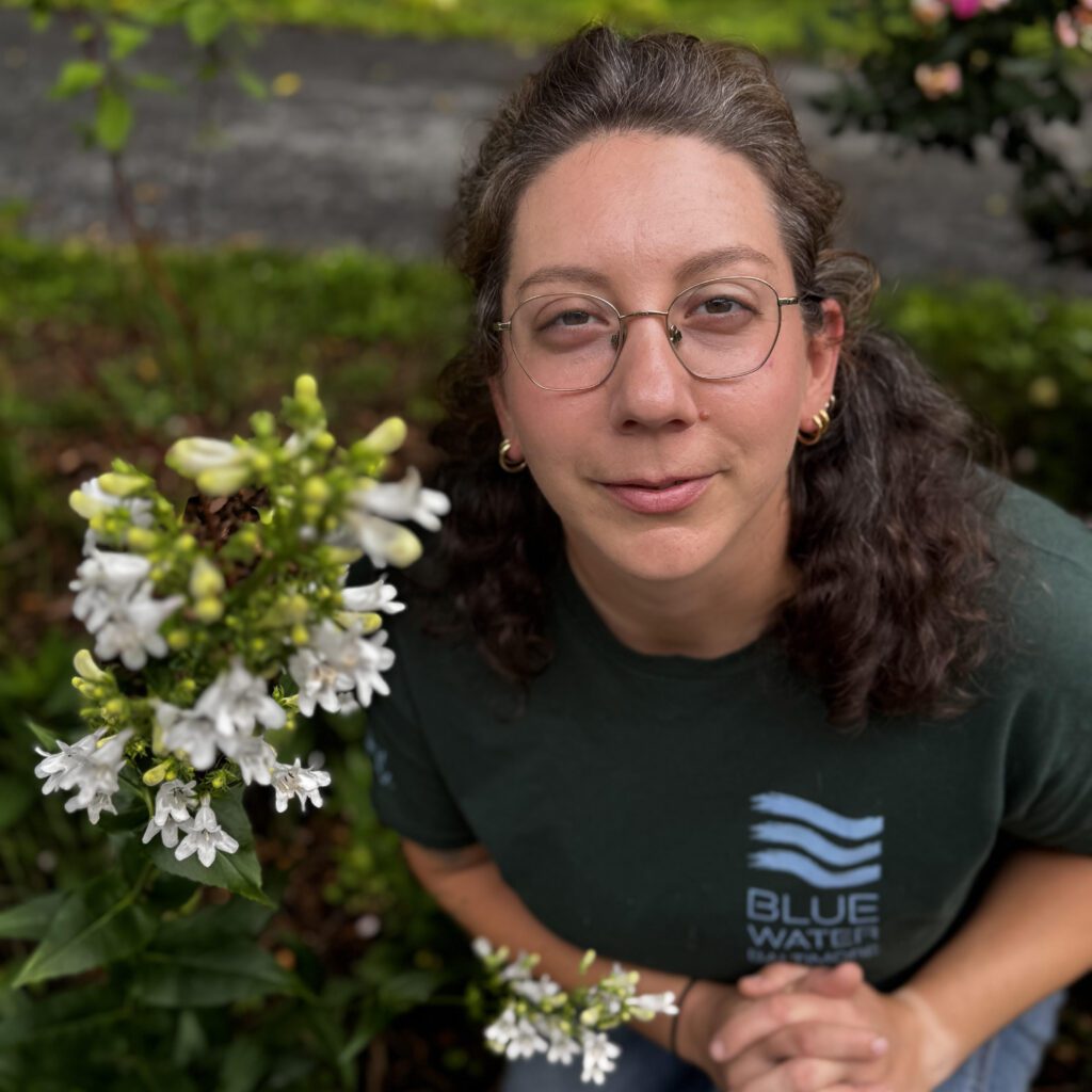 a woman kneeling down next to a bunch of flowers